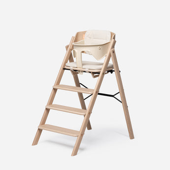 Light wood highchair with a cream reversible cushion set and beige baby seat.