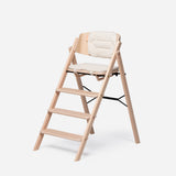 Light wood highchair with a cream, padded, reversible cushion set on the seat and backrest.