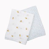 Two Lulujo cotton muslin swaddles: one white with bee print, one light blue with polka dots.