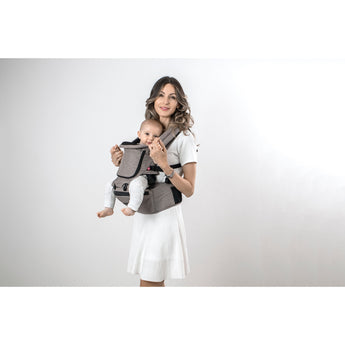 Woman in white dress carrying baby in a brown MiaMily Hipster Ergonomic Baby Carrier with hip seat.