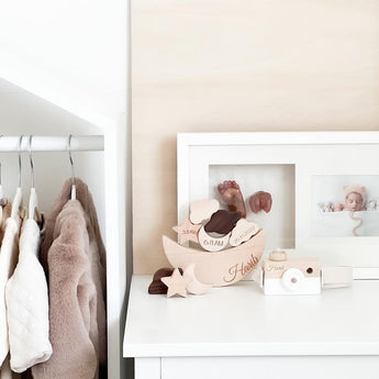 Personalized wooden camera toy with a white lens, next to a wooden moon sign with baby details.