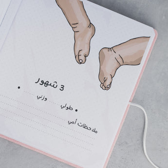 Open pink suede baby milestone album page with "3 شهور" (3 months), baby feet illustration, and dotted lines for details.