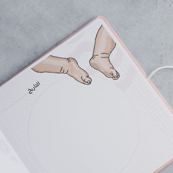 Open pink suede baby milestone album page with "التاريخ" and baby feet illustration.
