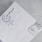 Open baby milestones photo album page with "Good night" in Arabic, moon, stars, and a window drawing.