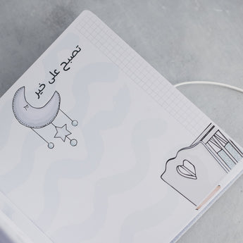 Open baby milestones photo album page with "Good night" in Arabic, moon, stars, and a window drawing.