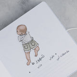 Open baby milestone photo album page with a hand-drawn baby illustration and Arabic text.