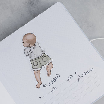 Open baby milestone photo album page with a hand-drawn baby illustration and Arabic text.