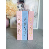 Three personalized suede baby milestone photo albums: two pink, one blue, with gold foil dates.