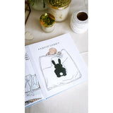 Open personalized baby milestones photo album with a sleeping baby and black bunny illustration.