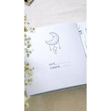 Open baby milestone photo album page with a moon and stars illustration, dotted lines for name/surname.