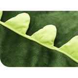 Close-up of a soft, dark green crocodile sleeping sack with bright green felt spikes along the edge.