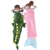 Kids in soft green crocodile and pink mermaid fun shaped sleeping sacks.