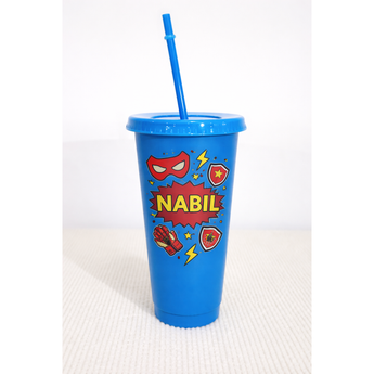 Blue 24oz personalized tumbler with "NABIL" in red, superhero mask, lightning bolts, and shield designs.