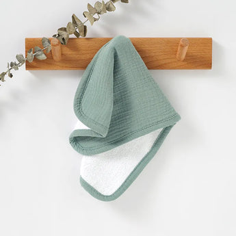 Soft green and white personalized baby burp cloth hanging on a wooden peg.