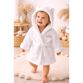 White organic cotton baby bathrobe with bear ears and "Mila" embroidered in pink.