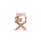 Personalized children's director chair made of French oak and white canvas, with "Beau" embroidered, holding a teddy bear.