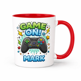 White 11 oz ceramic mug with red handle and interior, featuring a "Game On!" design, a black game controller, and "MARK" personalized text.