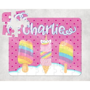 Personalized 60-piece kids puzzle with "Charlie" in white script, featuring two rainbow popsicles and a unicorn ice cream cone on a pink polka dot background.