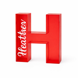 Red transparent acrylic letter H piggy bank with "Heathen" printed in white.