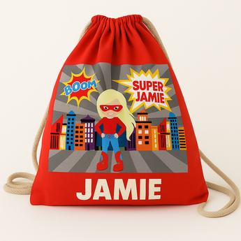 Red recycled cotton drawstring bag with a blonde superhero girl, city skyline, and "SUPER JAMIE" and "JAMIE" text.