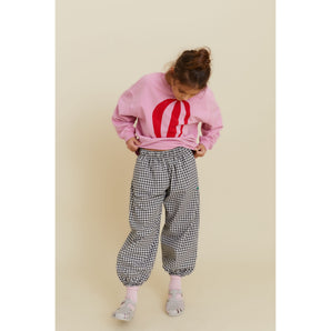 Girl in pink organic cotton oversized sweatshirt with red hot air balloon print and black and white gingham pants.