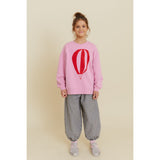 Girl in pink organic cotton oversized sweatshirt with red hot air balloon print and checkered pants.