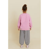 Kid in an oversized pink organic cotton sweatshirt with a hot air balloon print, viewed from the back.