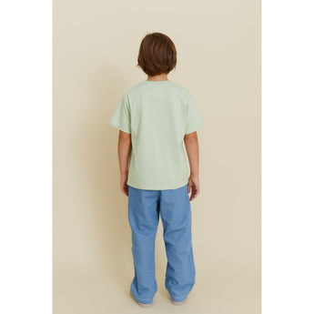 Kid wearing a light green organic cotton oversized t-shirt with a subtle potato print, paired with blue pants.