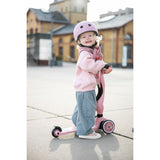 Happy toddler in pink helmet and outfit with a pink Scoot & Ride Highwaykick 1 scooter.