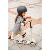 Young child in black helmet and pads riding a light gray 3-wheel Scoot & Ride Highwaykick 3S LED scooter.