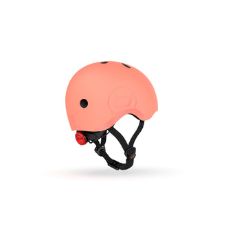 Scoot & Ride eco-friendly kids helmet in peach, featuring a red rear light and black straps.