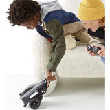Two kids playing with a black Sharper Image Remote Control Stunt Mongoose LED car, one touching it, the other holding the controller.
