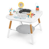 White Skip Hop Discoverosity 3 Stage Activity Center with wooden legs, rotating seat, and colorful toys.