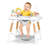 Happy baby in Skip Hop Discoverosity 3 Stage Activity Center with white tray, wooden legs, and colorful toys.