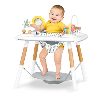 Happy baby in Skip Hop Discoverosity 3 Stage Activity Center with white tray, wooden legs, and colorful toys.