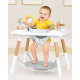 Happy baby in a white and wood Skip Hop Discoverosity 3 Stage Activity Center with colorful toys.