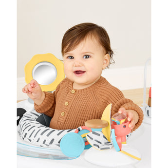 Happy baby in Skip Hop Discoverosity 3 Stage Activity Center with mirror, toys, and zebra-print seat.