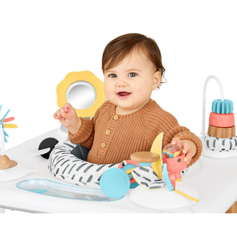 Smiling baby in a Skip Hop Discoverosity 3 Stage Activity Center with colorful toys.