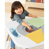 Happy toddler drawing at a white and gray Skip Hop activity center with storage.