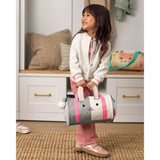 Smiling child holds a gray and white Skip Hop Duffimals bunny duffle bag with pink ears and handles.