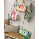 Three Skip Hop Duffimals kids duffle bags: a pink cat, gray bunny, and blue dinosaur, hanging in a mudroom.