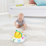 Yellow and white Skip Hop Follow Bee crawl toy with colorful lights on a rug, with a baby crawling in the background.
