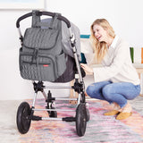 Gray quilted Skip Hop Forma nappy bag backpack hanging on a stroller, with a smiling woman.