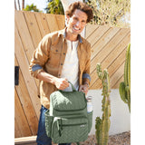 Smiling man holding a sage green quilted Skip Hop Forma backpack with a water bottle in its side pocket.