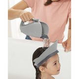 Gray Skip Hop Moby whale bath visor on a child's head, protecting eyes as water is poured.