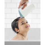White and blue Skip Hop Moby Waterfall Rinser used on a child's head during bath time.