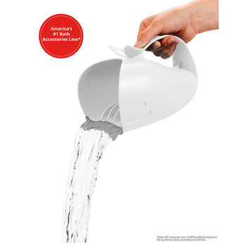 Hand holding a white Skip Hop Moby Waterfall Rinser, shaped like a whale, pouring water from its gray rubber lip.
