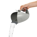 Hand holding a gray whale-shaped Skip Hop Moby Waterfall Rinser pouring water, with a soft rubber lip.