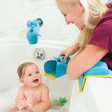 Happy baby in a tub, smiling as a woman rinses their hair with a blue whale-shaped Skip Hop Moby rinser.