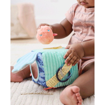 Baby playing with a soft, multi-textured Skip Hop Seascape Activity Cube, featuring a peach puffer fish rattle.